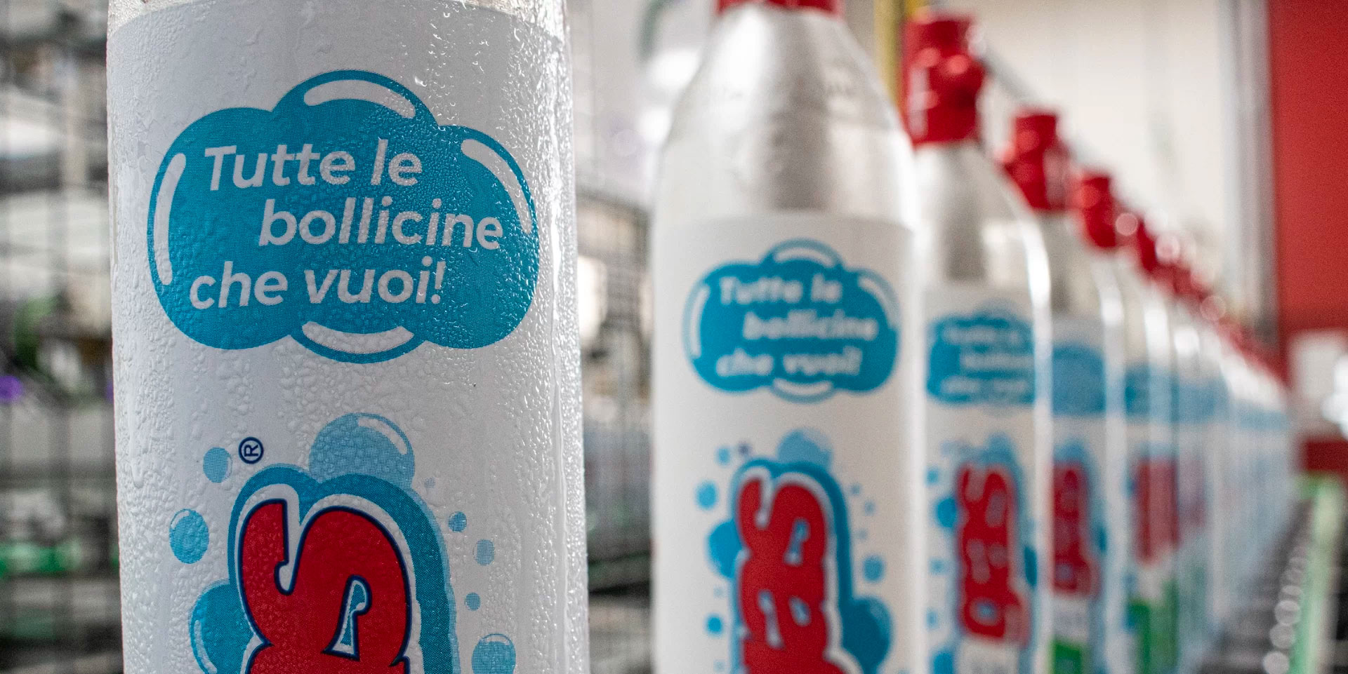 Primo piano su bottiglia d'acqua frizzante con una scritta "Tutte le bollicine che vuoi!".